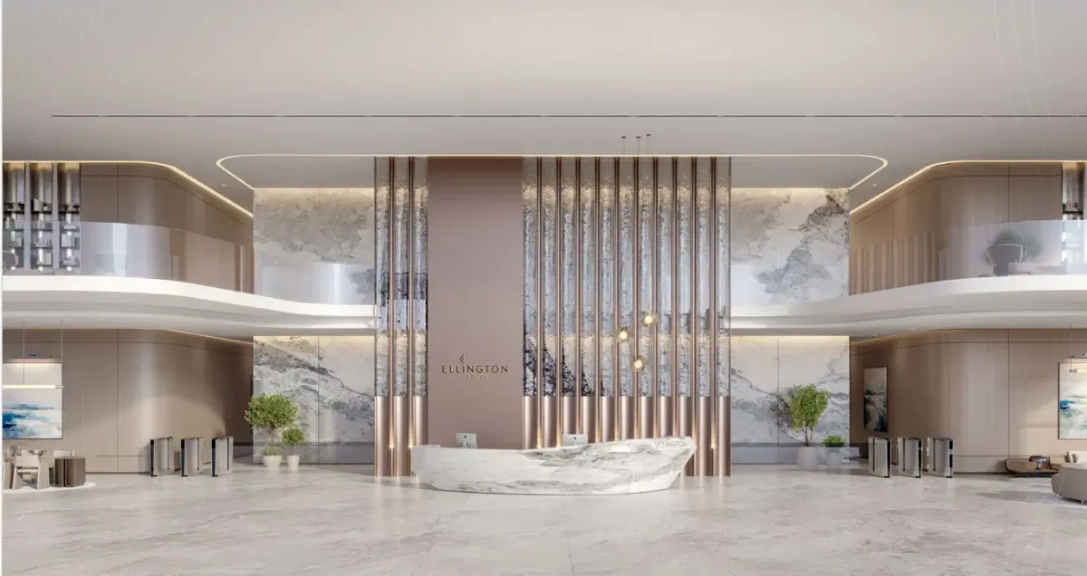 Double-height lobby with a marble reception desk framed by vertical bronze fins at Ellington Berkeley Tower